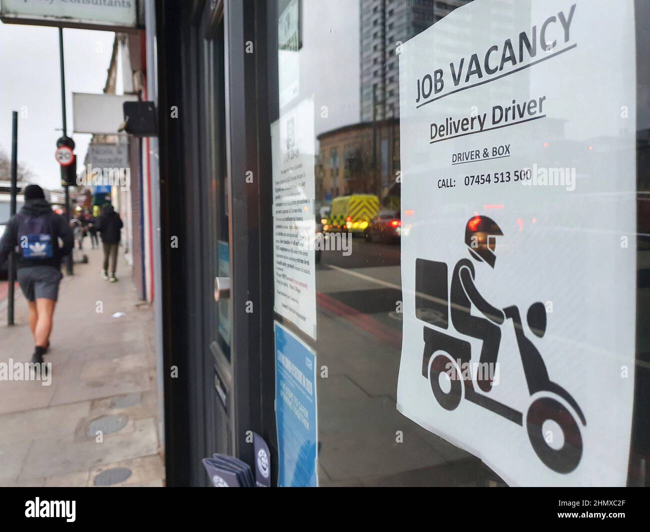 London, UK, 7 February 2022: a take-away food restaurant in Battersea has a sign in the door advertising a job vacancy for a delivery driver. Anna Wat Stock Photo