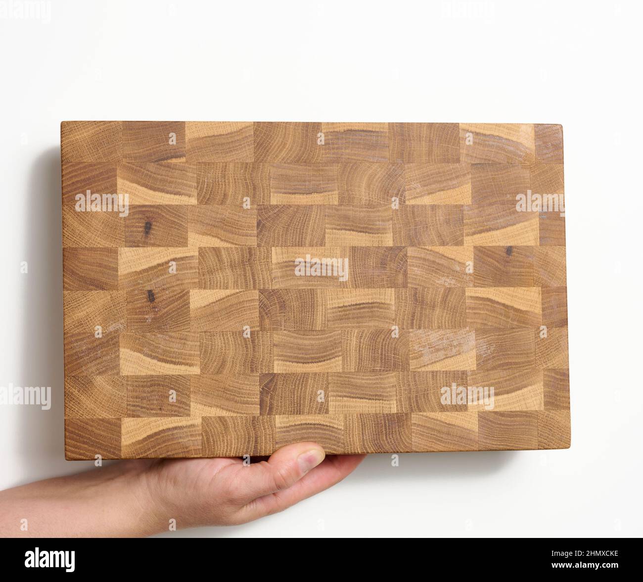 female hands hold empty rectangular brown wooden chopping board on white background Stock Photo