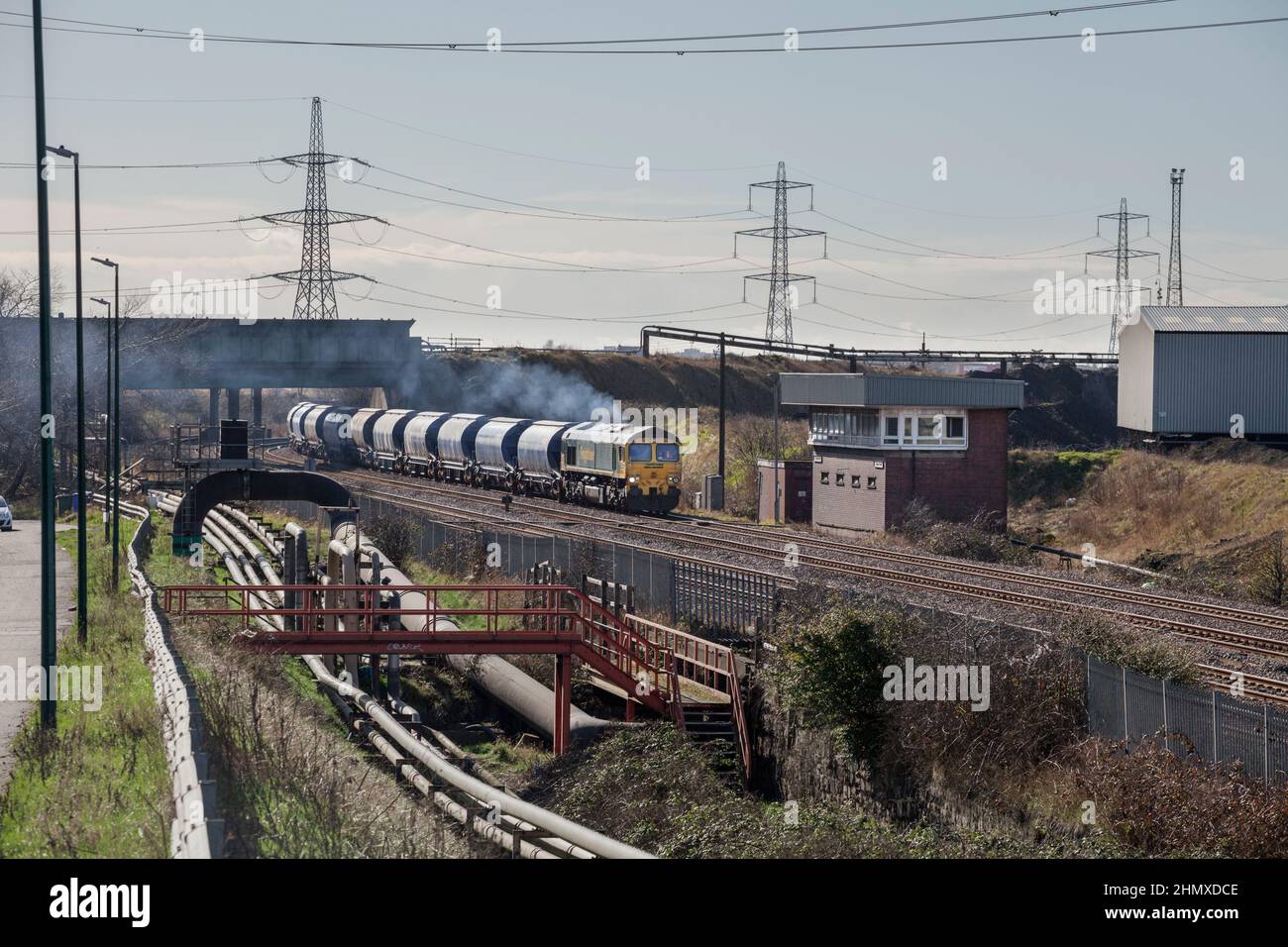 A Freightliner class 66 locomotive passes Grangetown signal box (Teesside) with a freight train  carrying potash for export Stock Photo