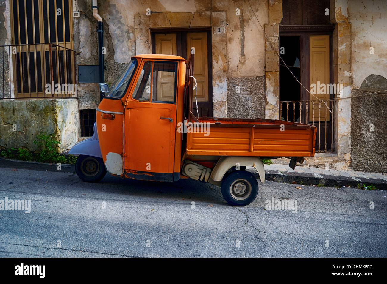 Piaggio Ape, light three-wheeled vehicle.Piaggio ape open backed van parked it Italian piazza. Piaggio Ape, three-wheeled light commercial vehicle. It Stock Photo