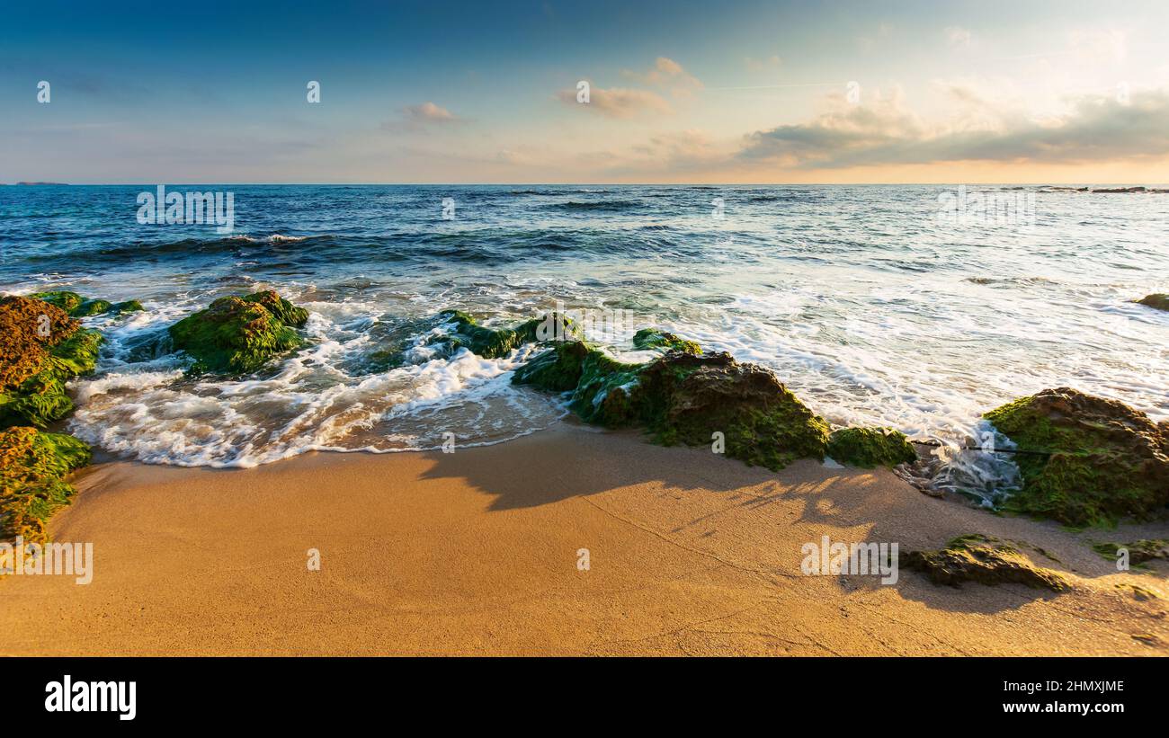 calm morning scenery at the beach. wonderful summer vacation background. calm waves washes the shore. blue sky with some clouds glowing in morning lig Stock Photo