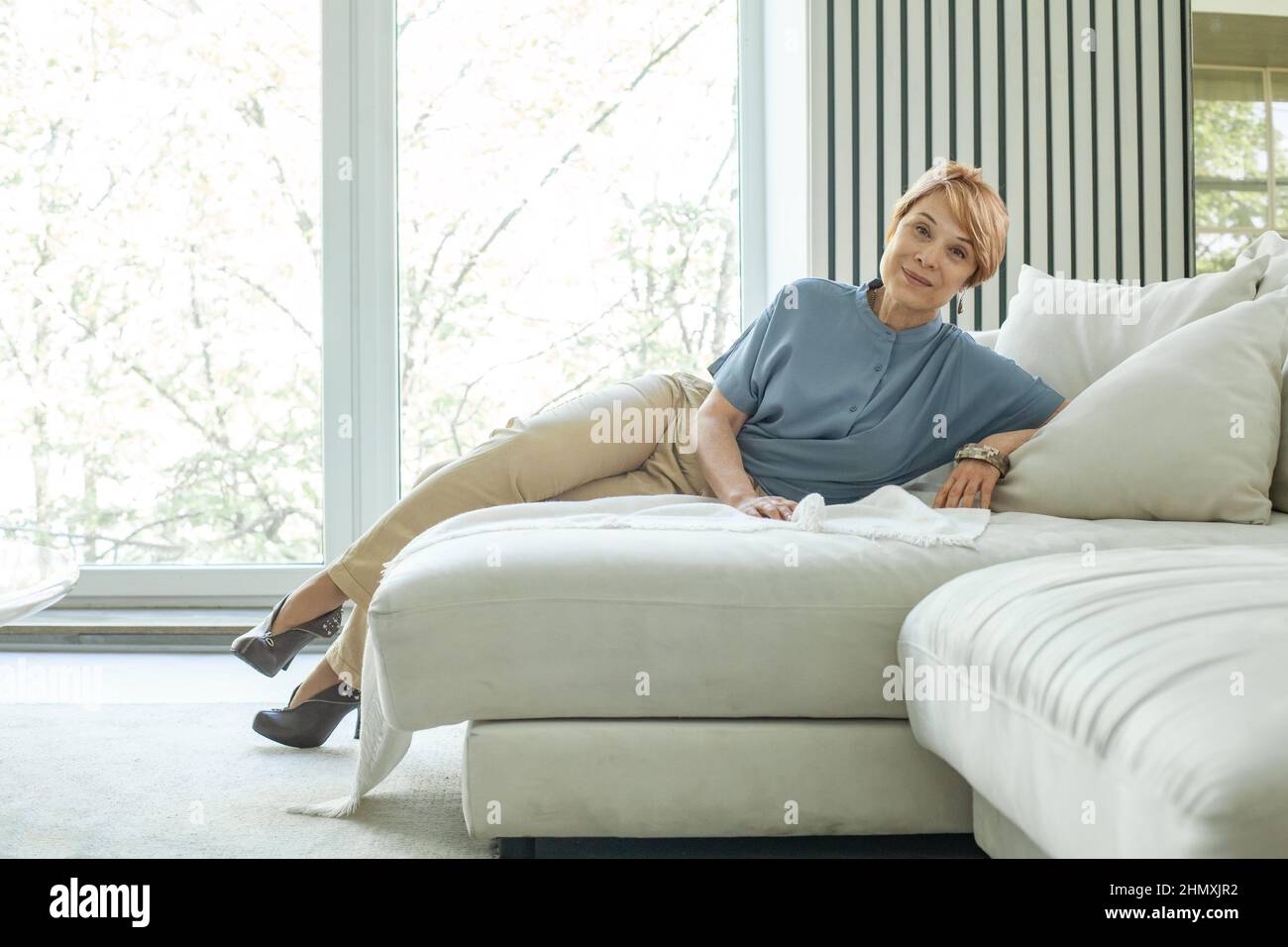 Happy mature woman relaxing by the window Stock Photo - Alamy