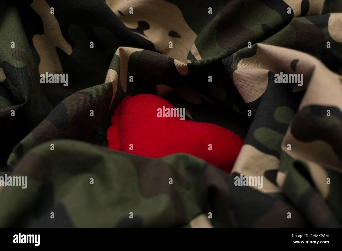 Red heart on military uniform. Love and war concept Stock Photo
