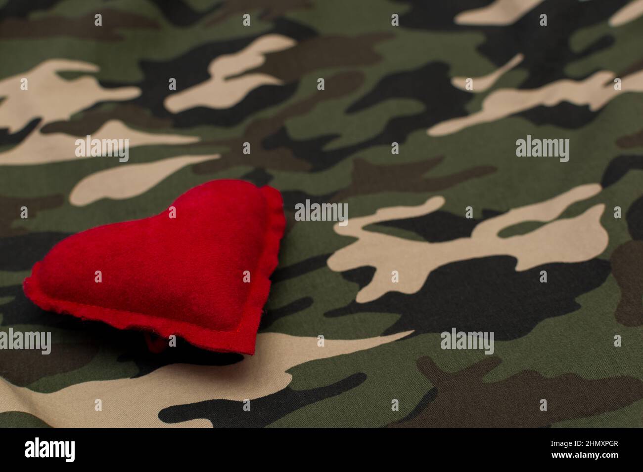 Red heart on military uniform with copy space. Love and war concept Stock Photo