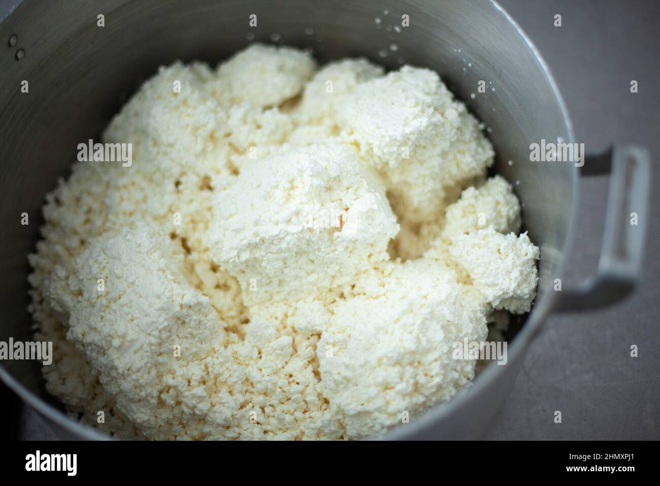 Cottage cheese in saucepan. Food in dining room. Cooking lunch in school kitchen. Dairy products. Chef's job. Making cheesecakes. Delicious and health Stock Photo