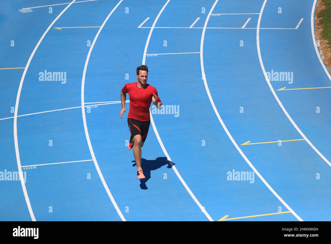 Running man professional athlete runner working out on track and field sport stadium. Top view of male sports person training hiit workout in Stock Photo