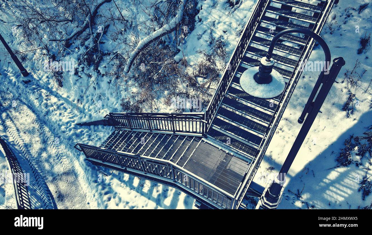 High angle view of snow covered urban stairs to the bridge above. Stock Photo