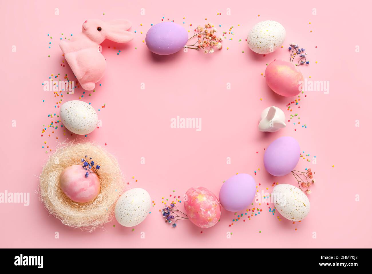Frame made of painted Easter eggs, bunnies and flowers on pink ...
