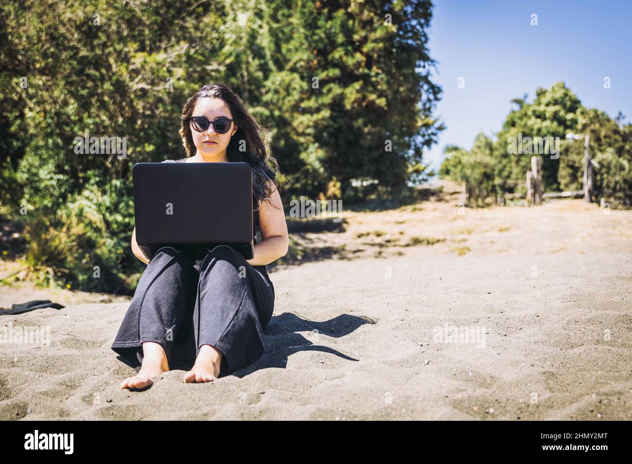 Young woman doing remote online work from the beach. Teleworking concept.  Stock Photo