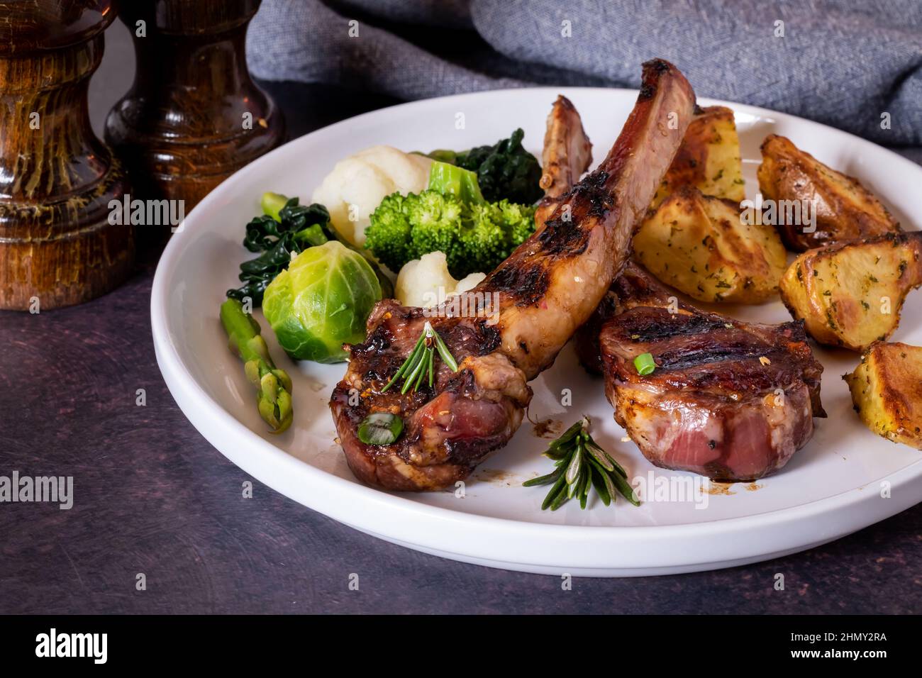Close up of lamb chops with sides of roasted potatoes and vegetables