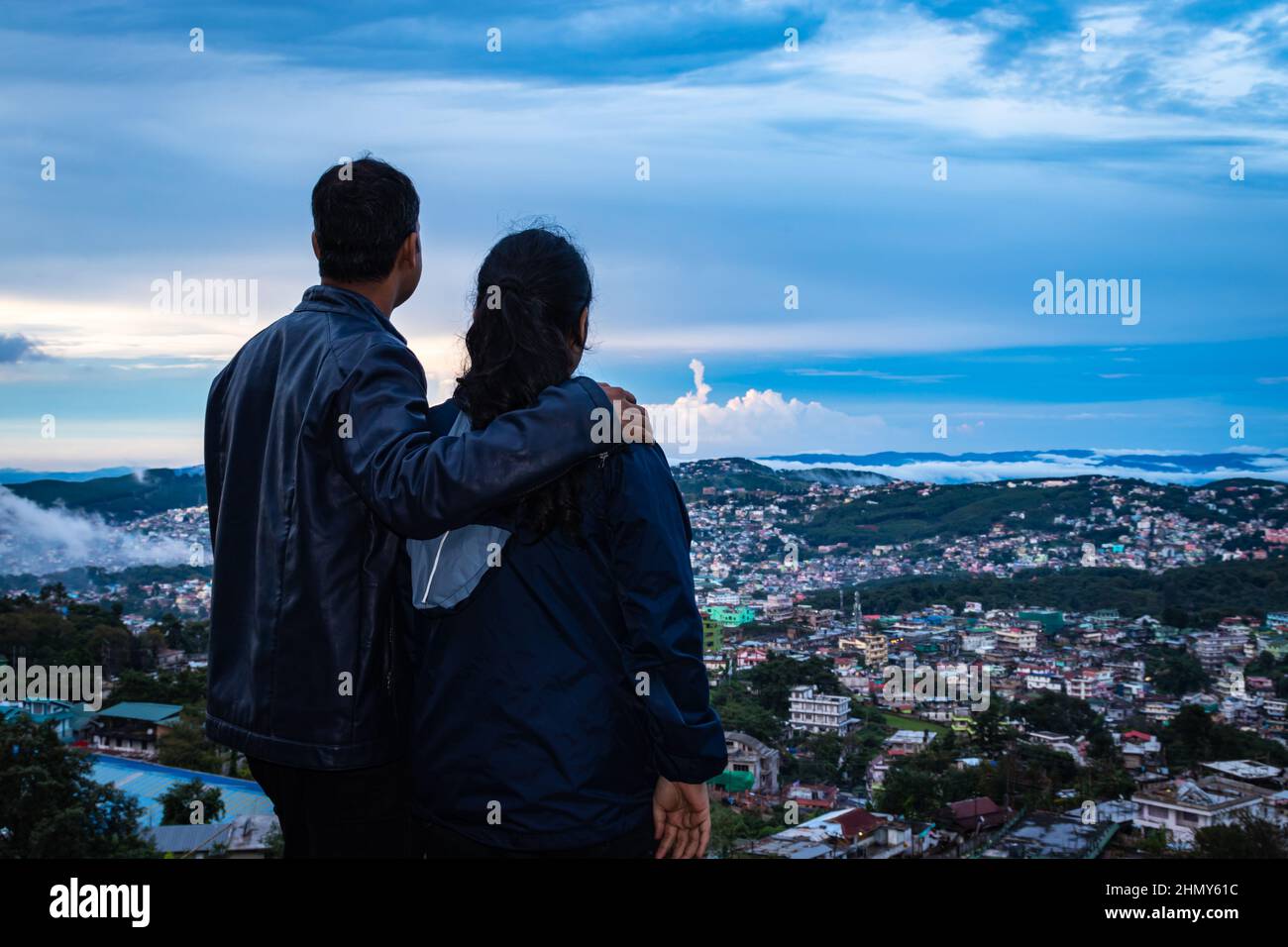 young couple watching downtown city view with dramatic cloudy sky at