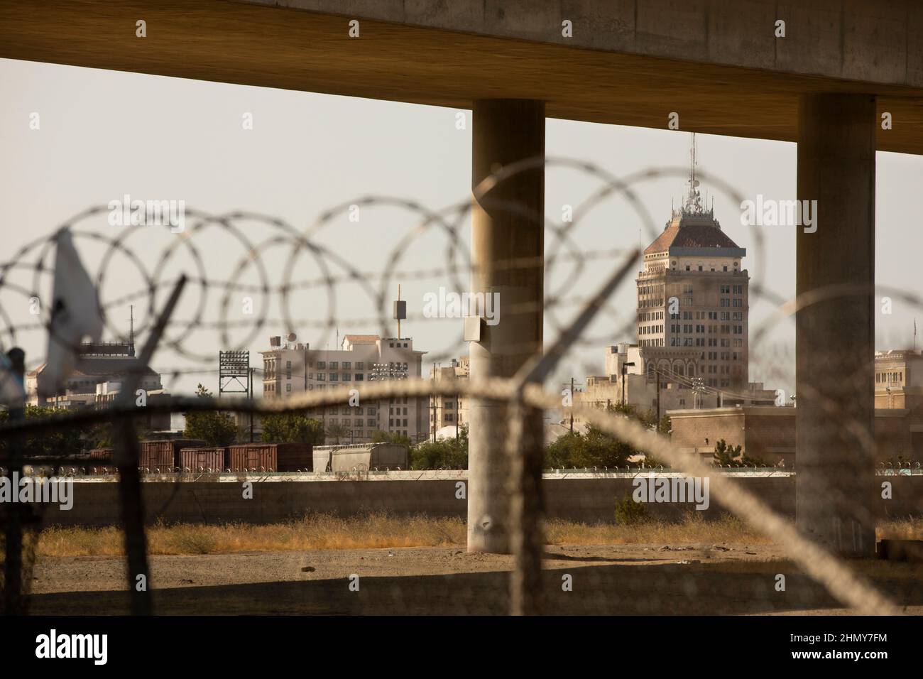 Barbed wire and a concrete overpass frame the downtown skyline of Fresno, California, USA. Stock Photo