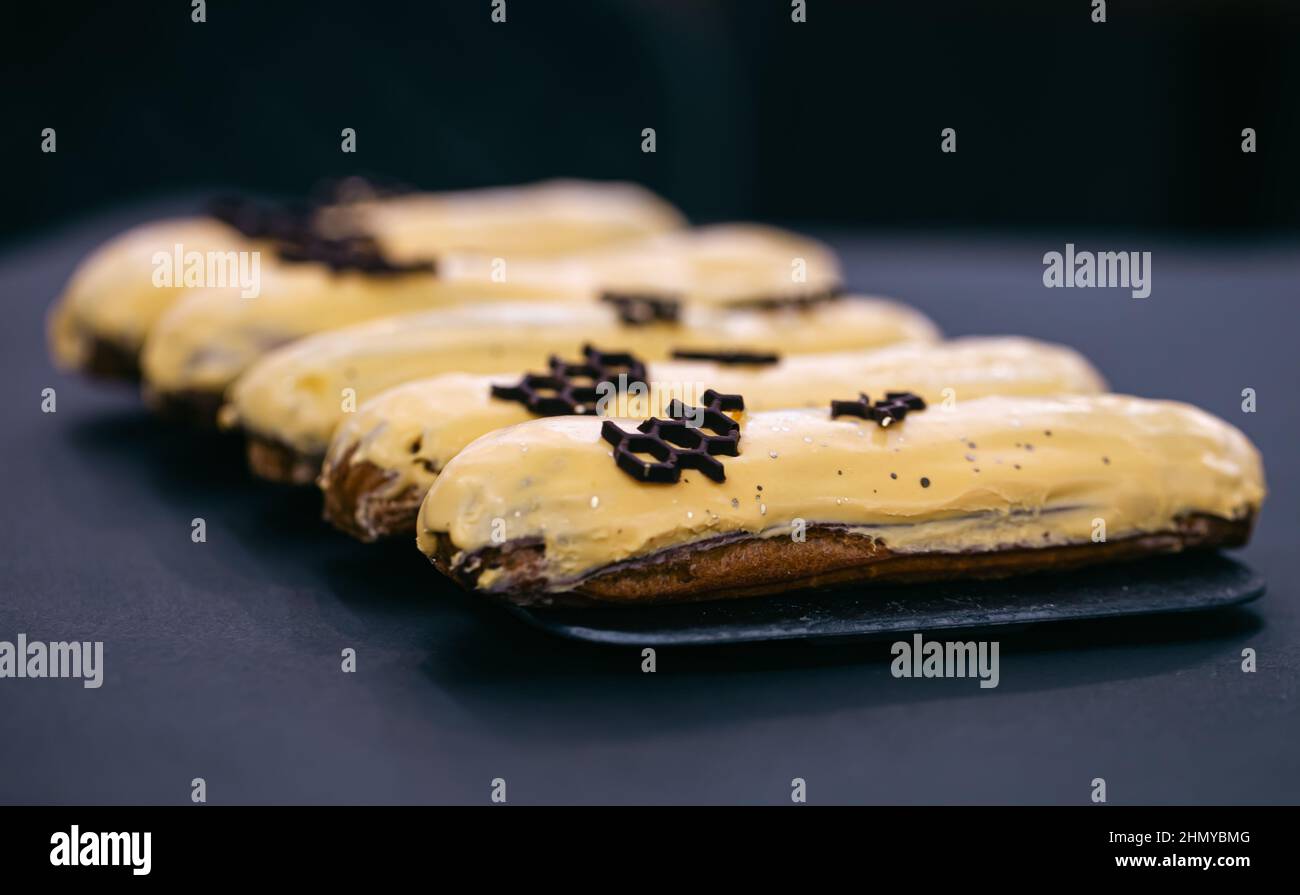 Close-up of eclairs in yellow glaze on a black background. Stock Photo