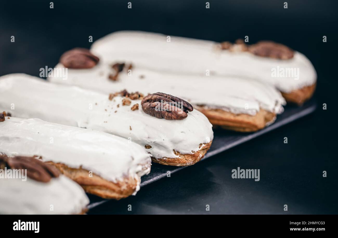 Close-up of eclairs in white glaze with pecans. Stock Photo