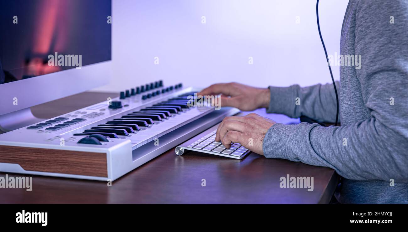 Male musician creates music using computer and keyboard, musician