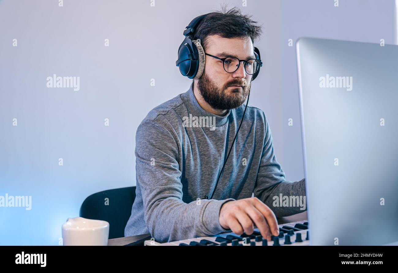 Male musician creates music using computer and keyboard, musician ...