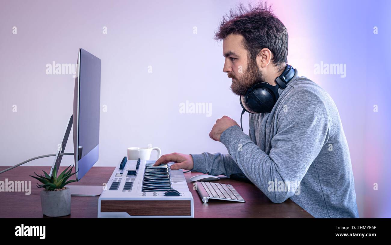 Male musician creates music using computer and keyboard, musician ...