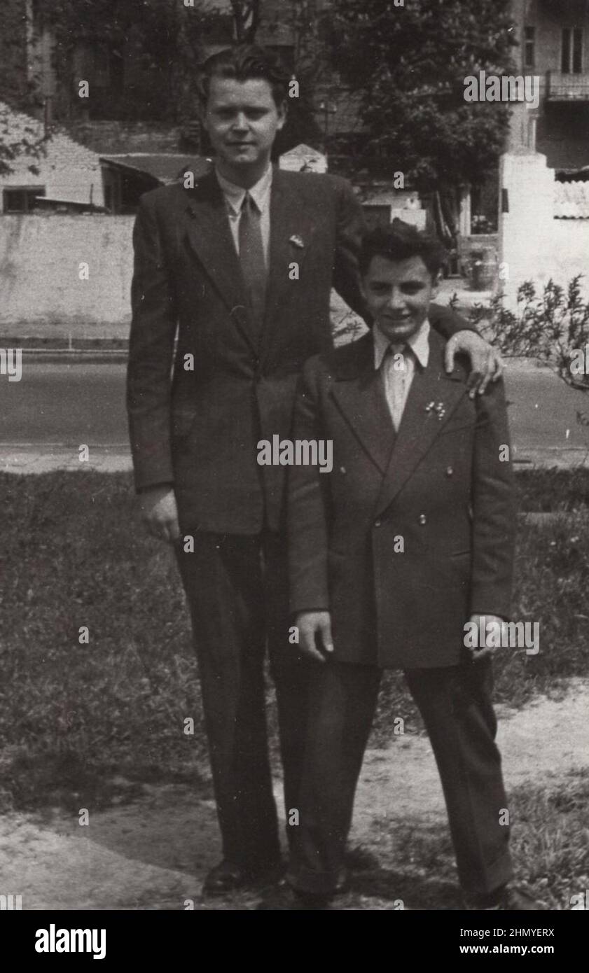 Vintage photo about brothers. Older brother lying his hand on his younger brother's shoulder. He is much taller than his younger bro. 1930s photo and they are very smart, elegant wearing suit.  source: original photographs ADDITIONAL-RIGHTS-CLEARANCE-INFO-NOT-AVAILABLE Stock Photo