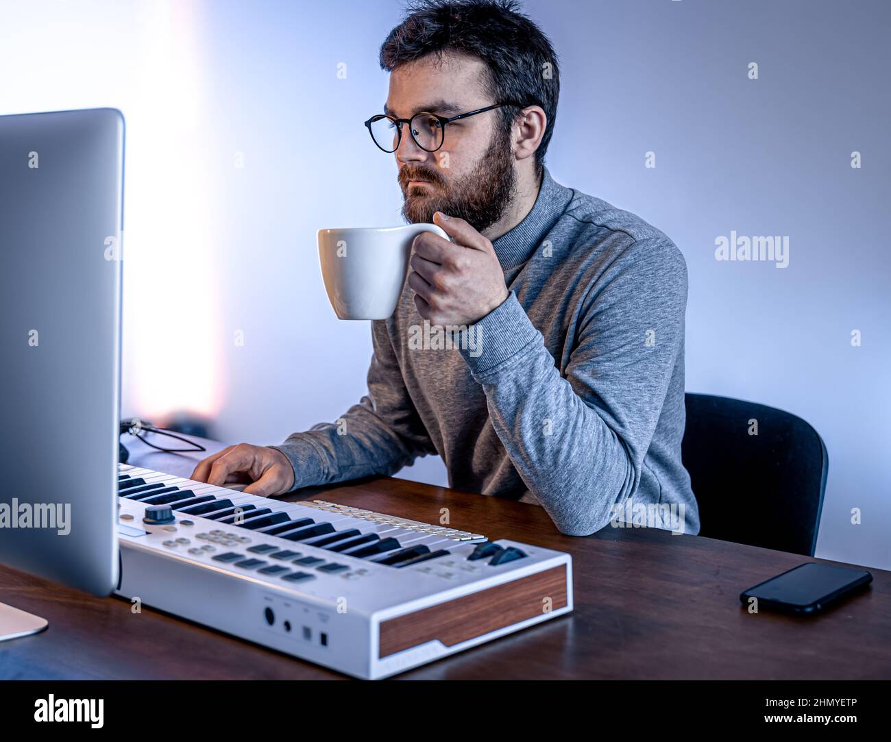Male musician creates music using computer and keyboard, musician ...