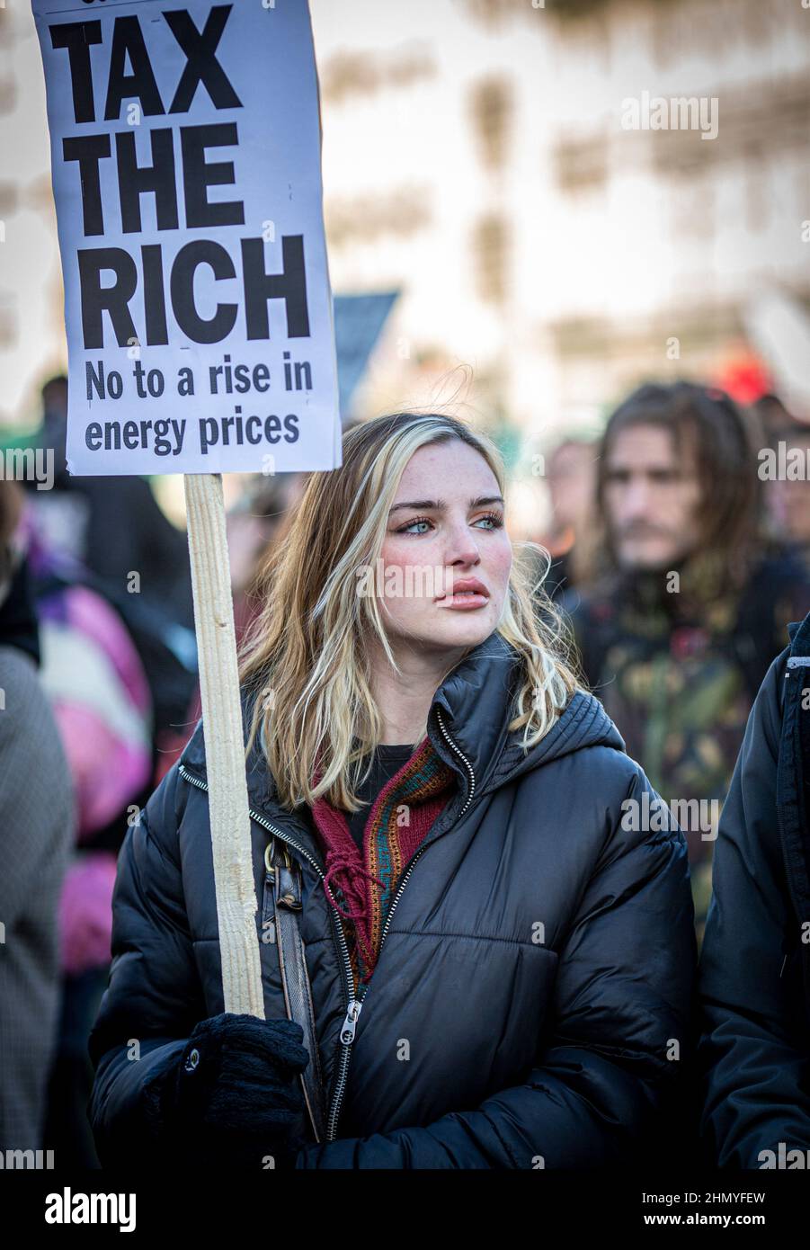 Young woman protest against the rises in fuel prices and costs of living holding a sign Tax The Rich in London . Stock Photo