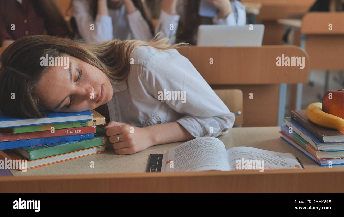 A Tired Schoolgirl Falls Asleep Over Her Textbooks At Her Desk Stock