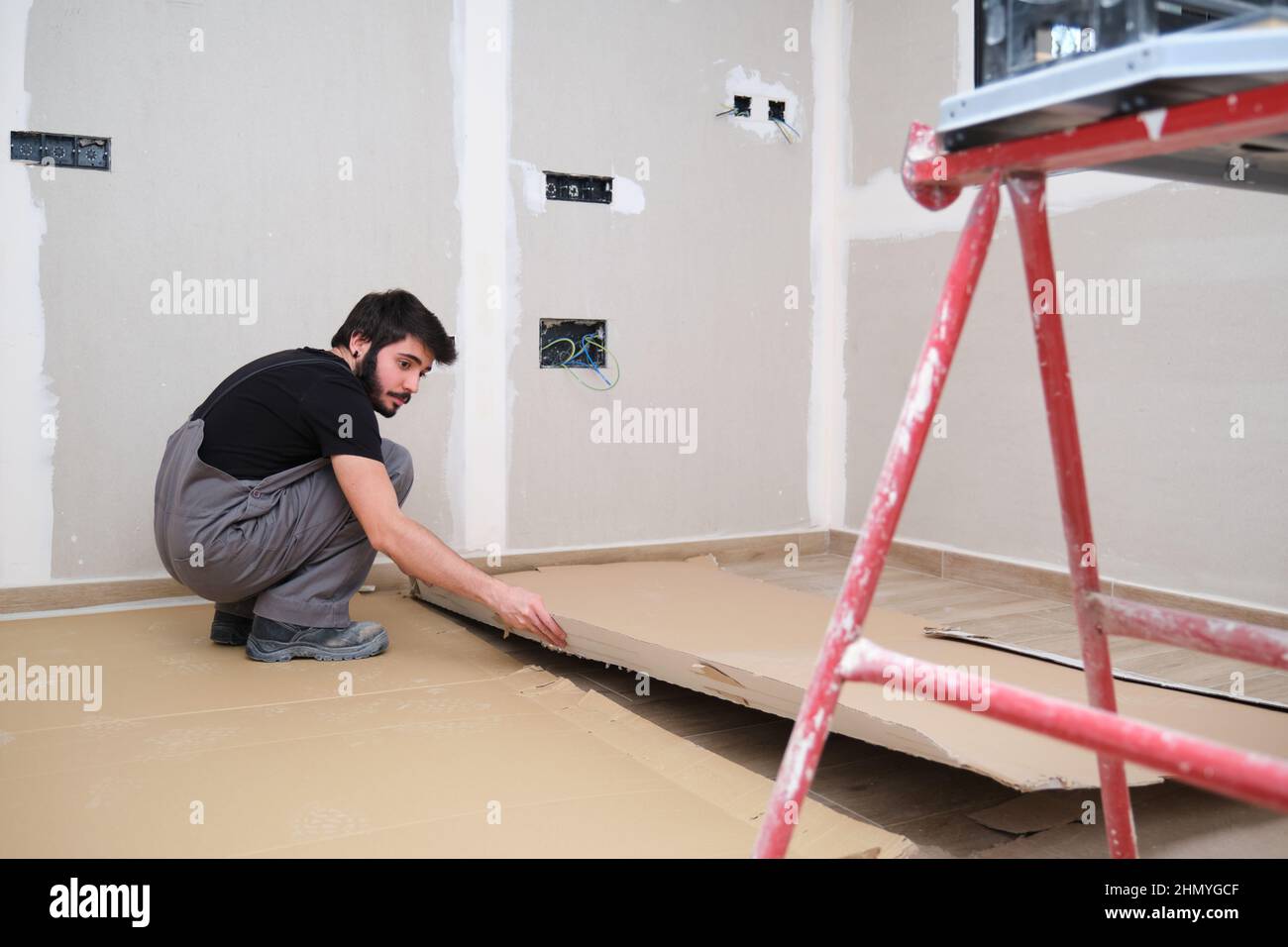 Painter using cardboard to cover the wood floor before painting the