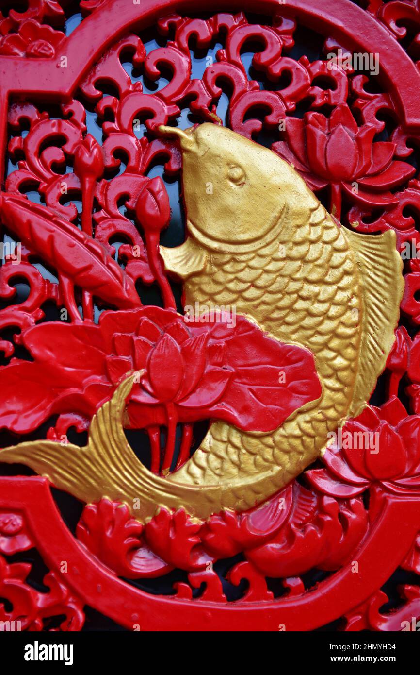 Closeup of a golden fish statue on a red fence Stock Photo Alamy