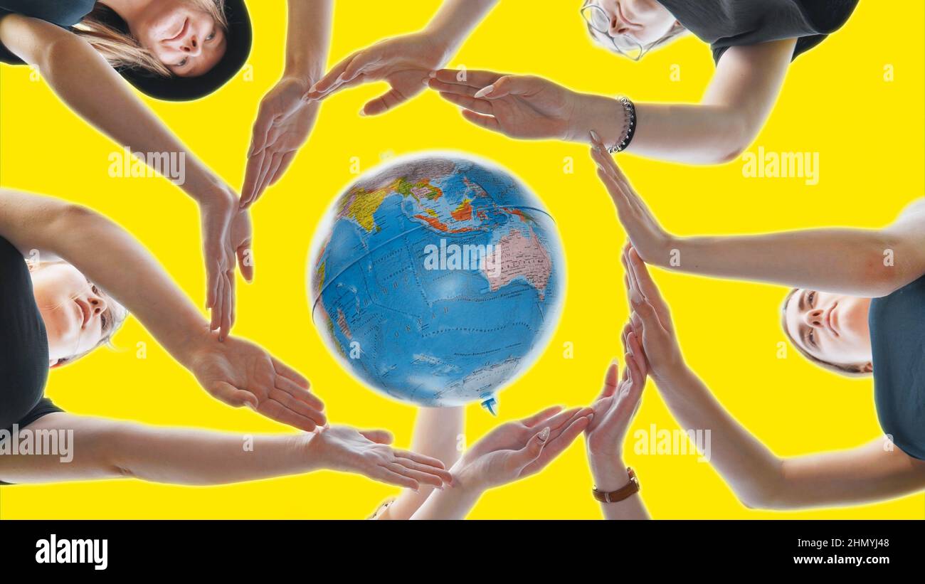 Schoolgirls hug the earth globe with their hands, making a circle out