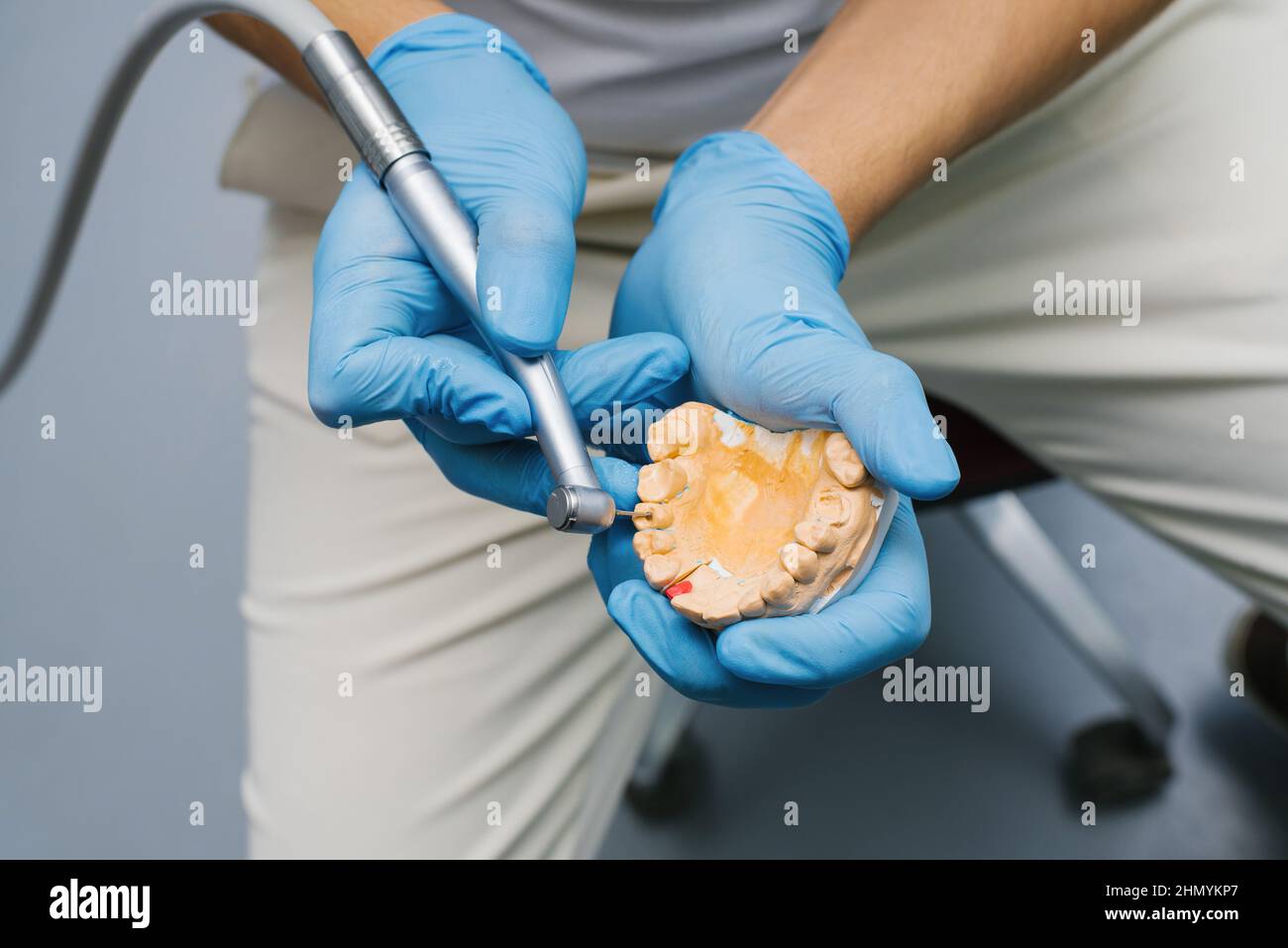 Dentist shows how to drill a tooth with a drill on a plaster model of a