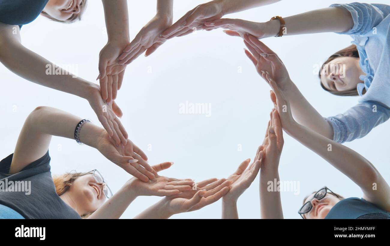 Friends make a circle with their palms against the blue sky. Stock Photo