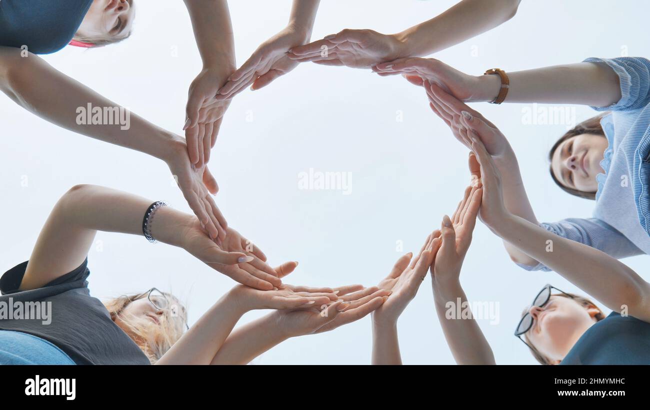 Friends make a circle with their palms against the blue sky. Stock Photo