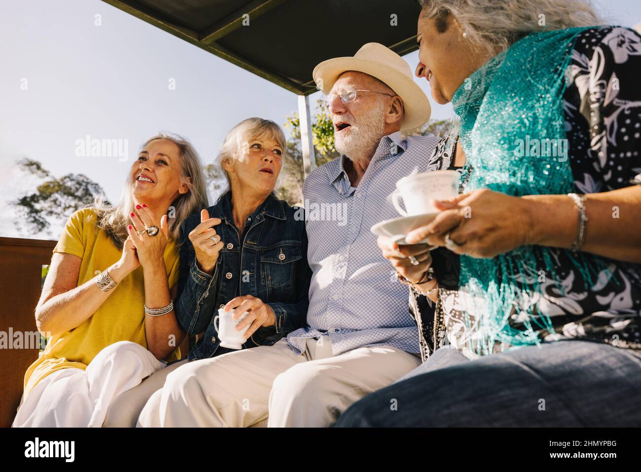 Old time friends laughing happily while having tea together. Cheerful elderly people enjoying their summer vacation at a spa resort. Senior citizens h Stock Photo