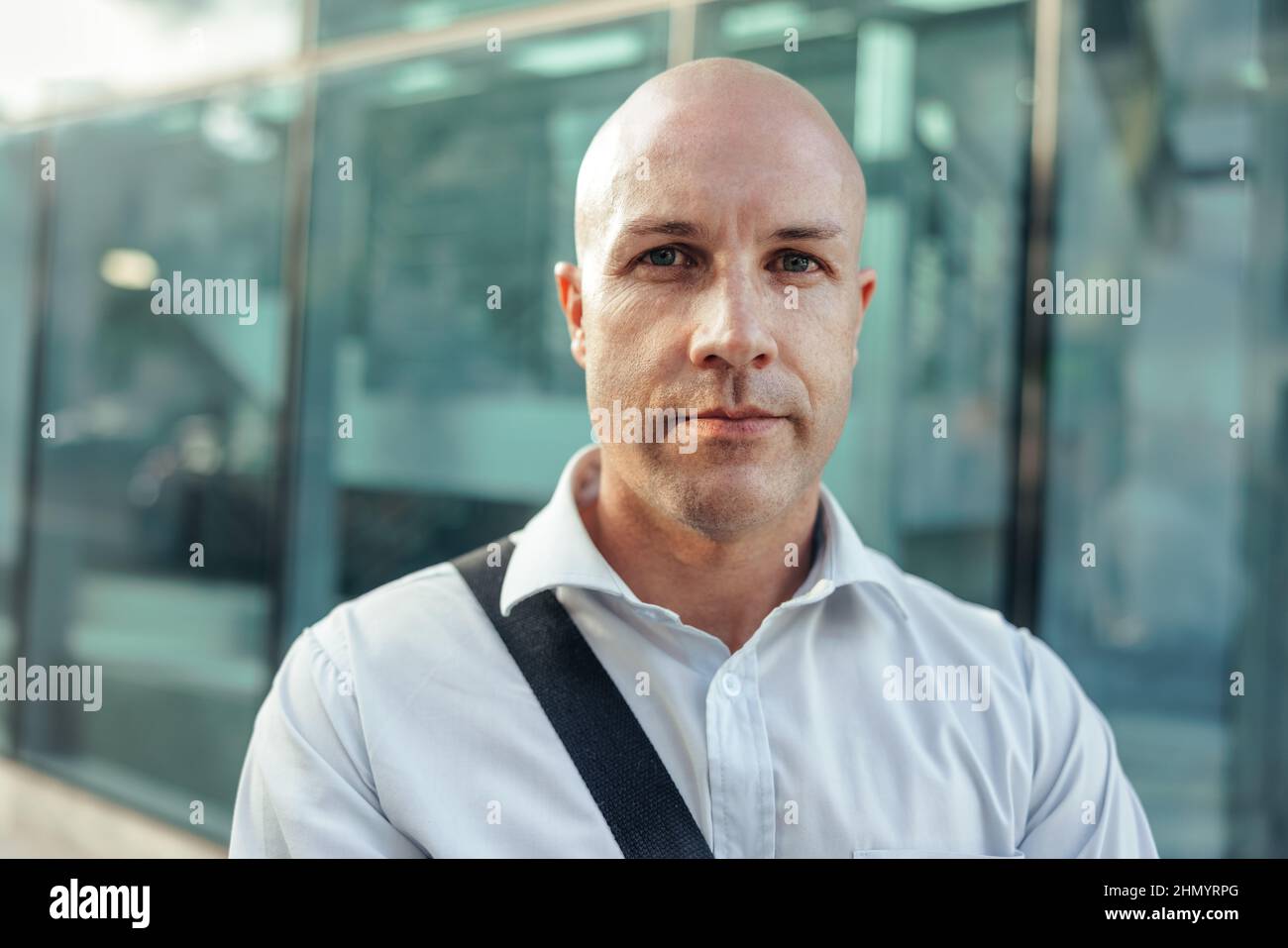 Businessman looking at the camera confidently while standing in front of a high rise office building in the city. Mid-adult entrepreneur standing alon Stock Photo