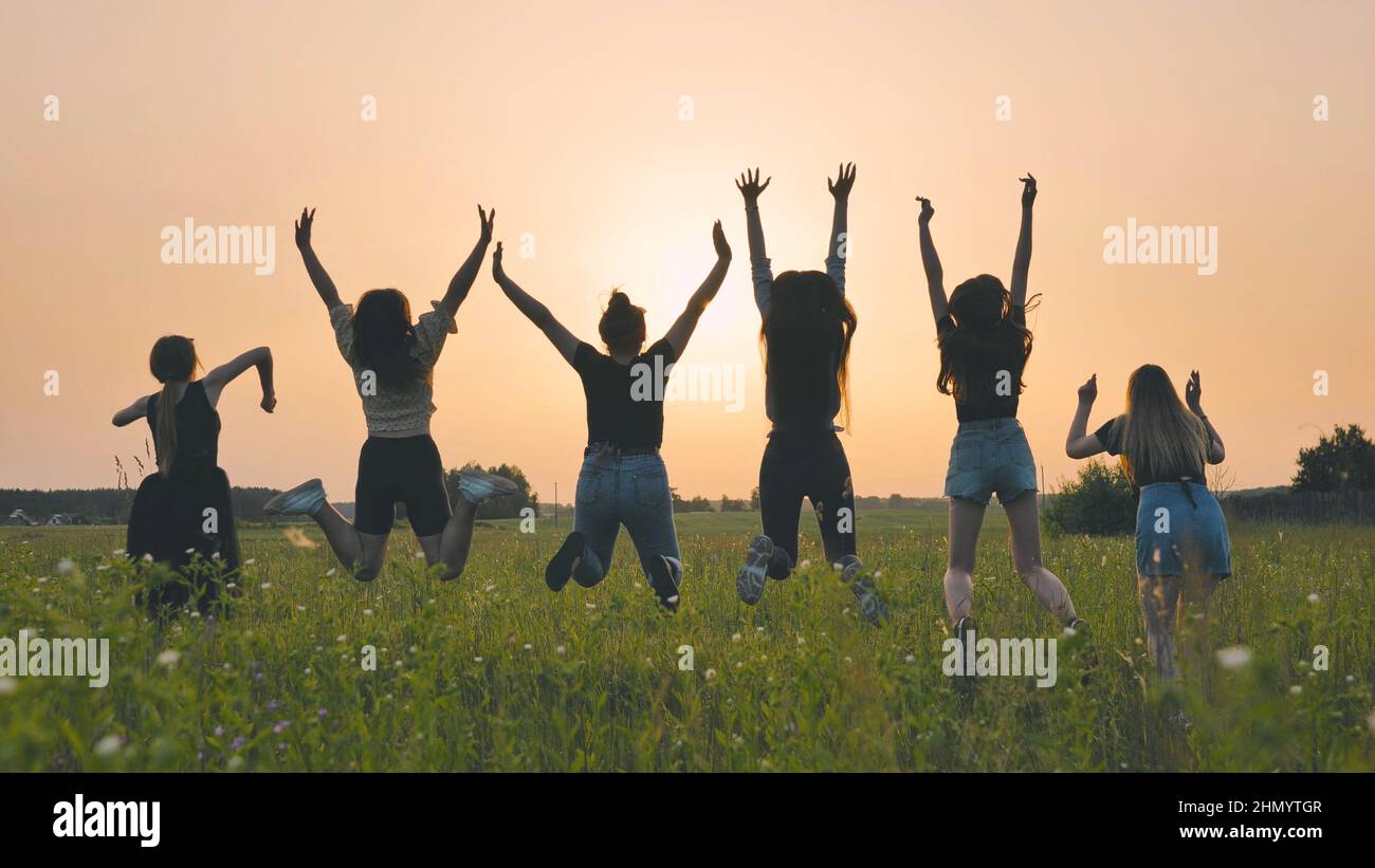 Girls friends are jumping against the background of an evening ...