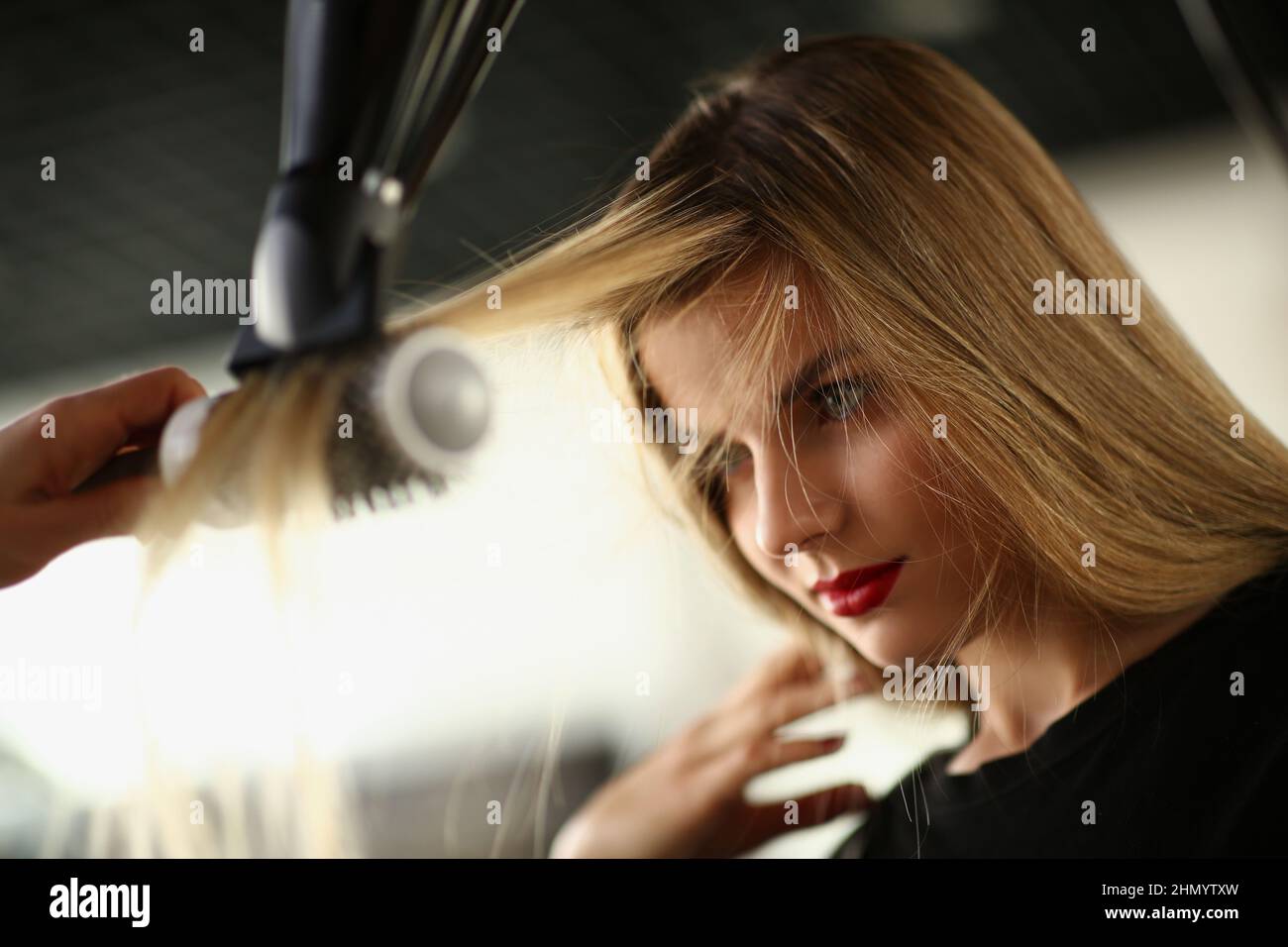 Hairdresser using hairdryer tool to dry clients lock of hair Stock