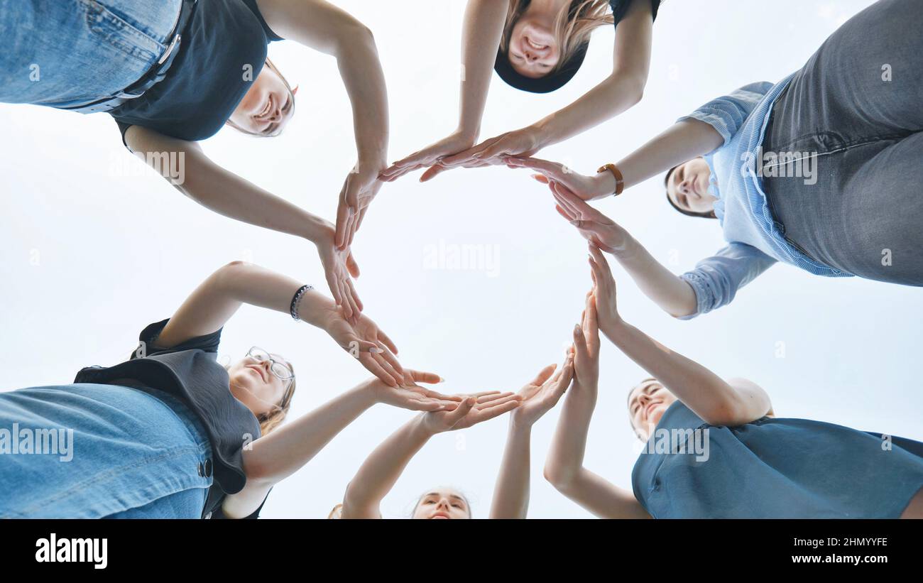 Friends make a circle with their palms against the blue sky. Stock Photo