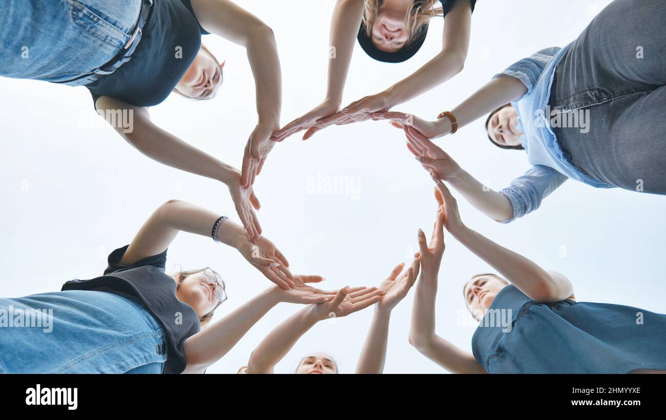 Friends make a circle with their palms against the blue sky. Stock Photo
