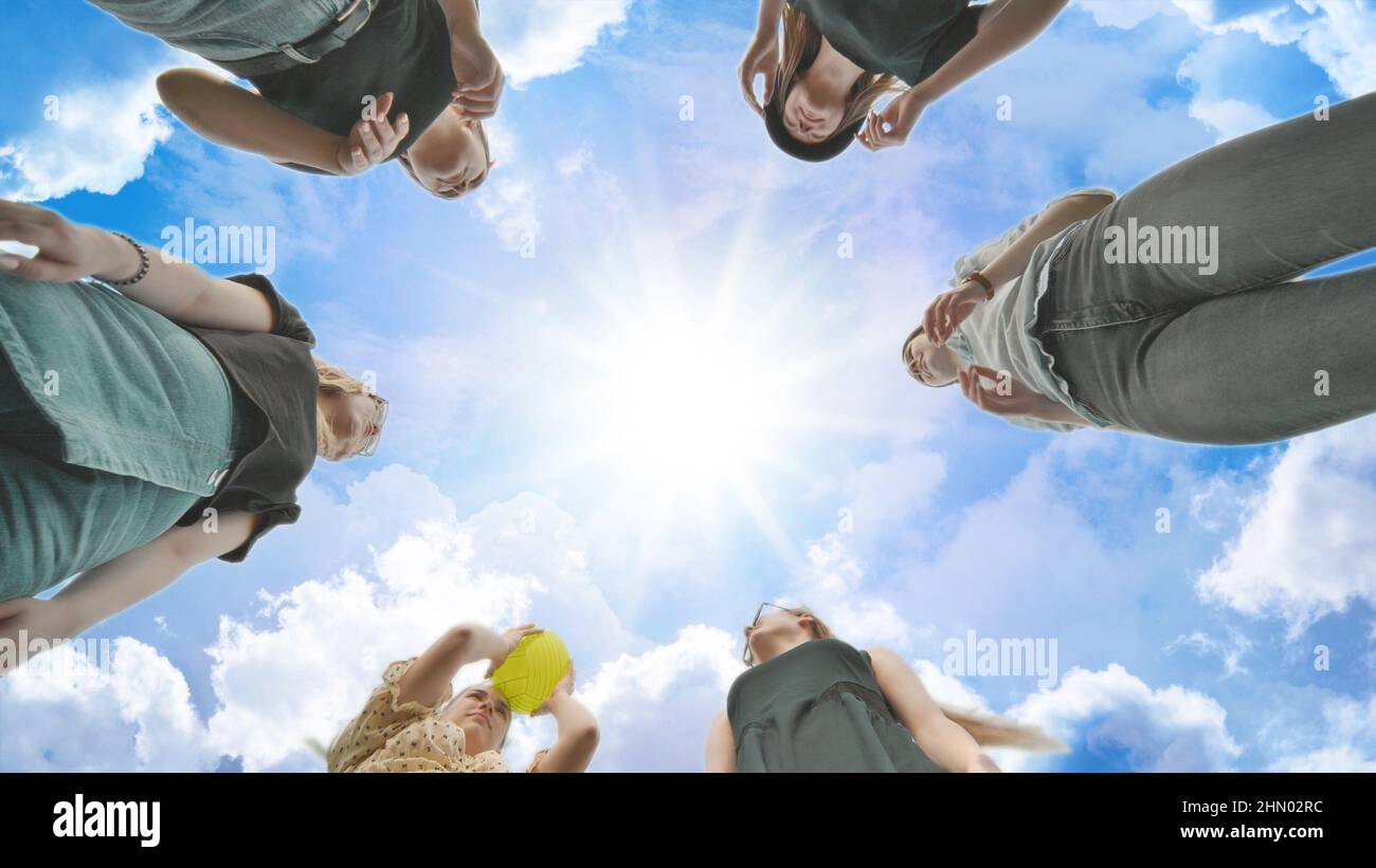 Girlfriends throw the ball to each other against the blue sky. Stock Photo