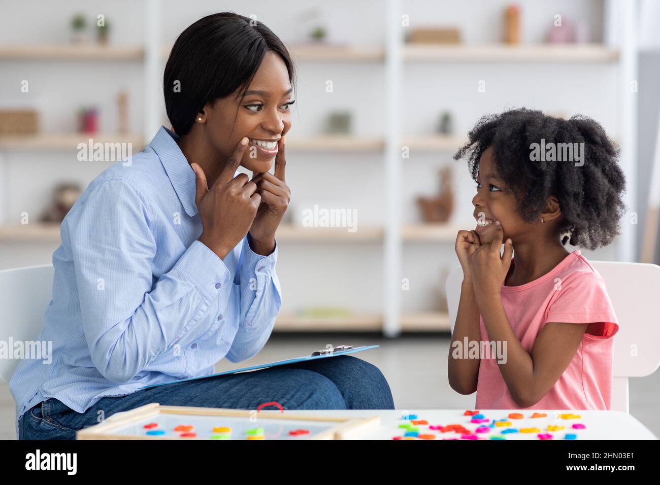 Speech therapist working with little girl at clinic Stock Photo