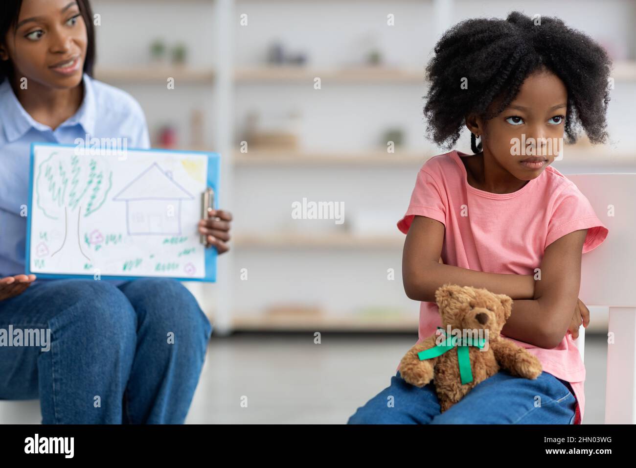 Child psychotherapist showing little girl clipboard with drawing Stock Photo