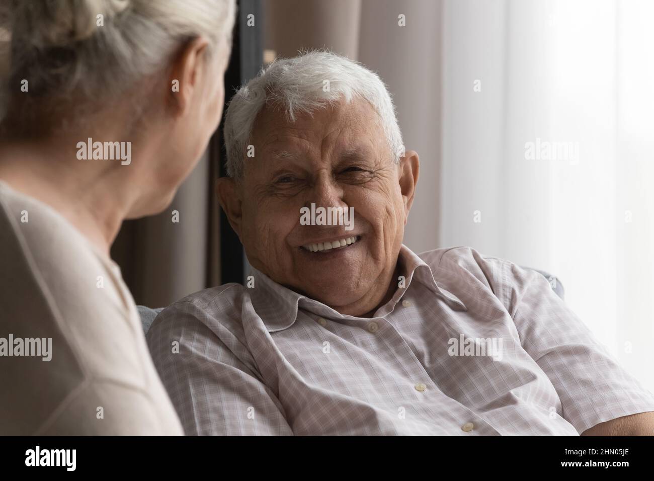 Happy elderly man talking to wife, female carer at home Stock Photo