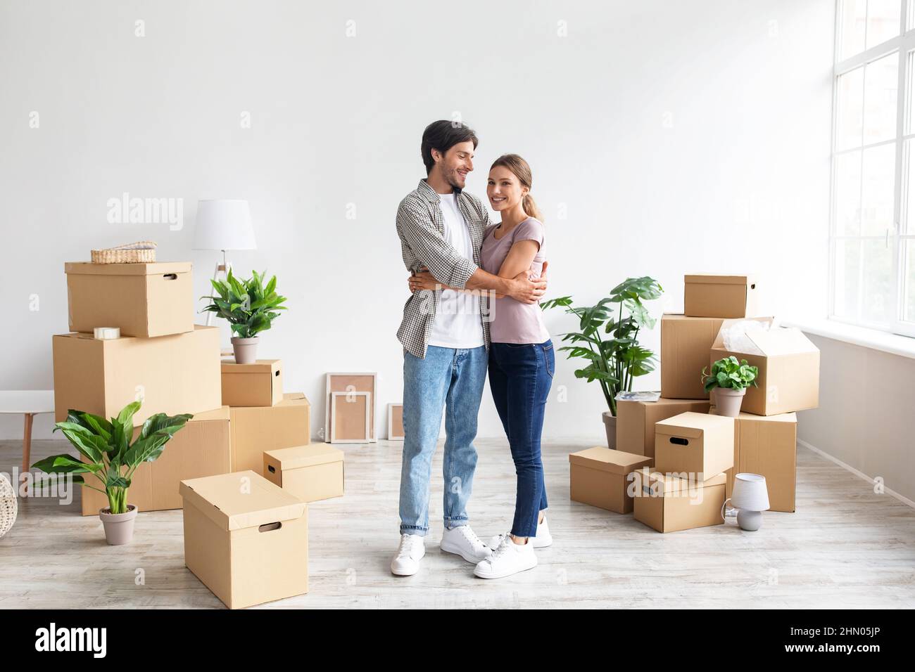 Glad european millennial wife and husband in casual hugging in room ...