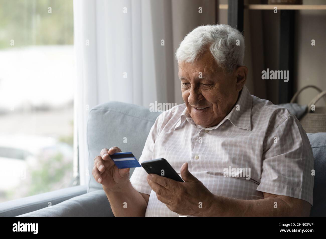 Focused man using mobile phone and making online payment Stock Photo