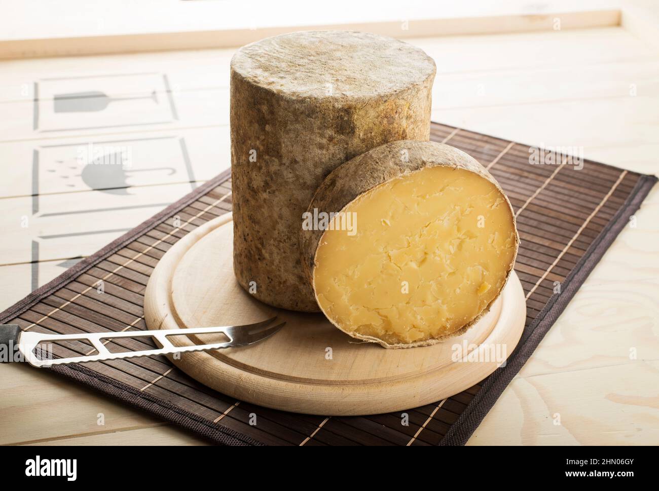 Cheddar PDO cheese cut and served on a wooden plate. Stock Photo
