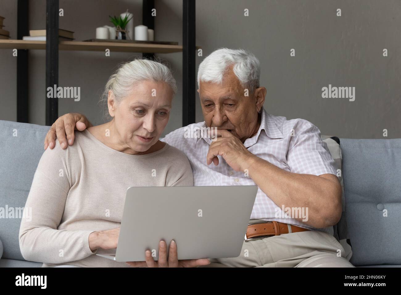 Focused serious elder couple using online app, banking service Stock Photo