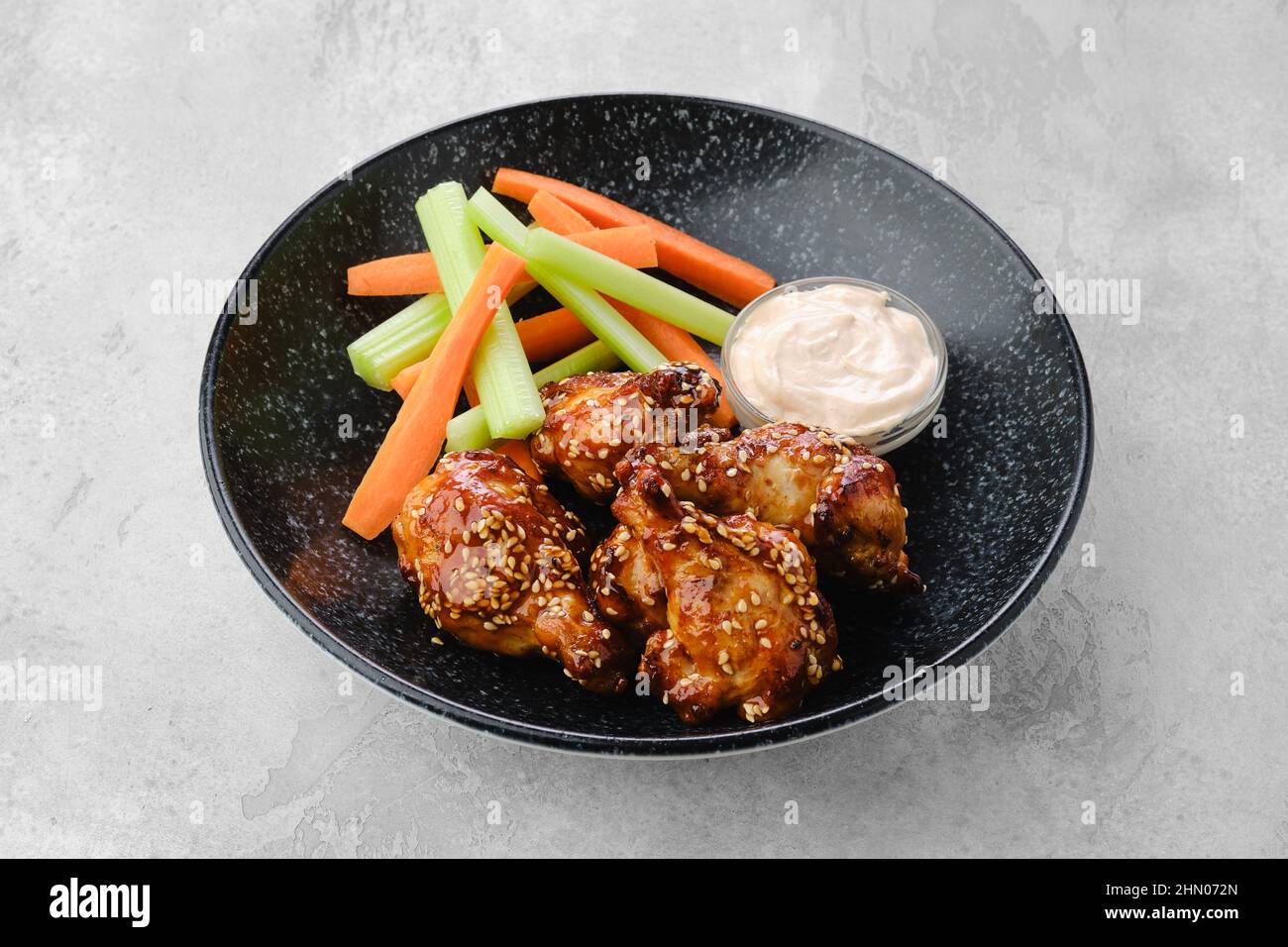 Fried chicken legs with teriyaki sauce and slices of celery and carrot on a plate Stock Photo
