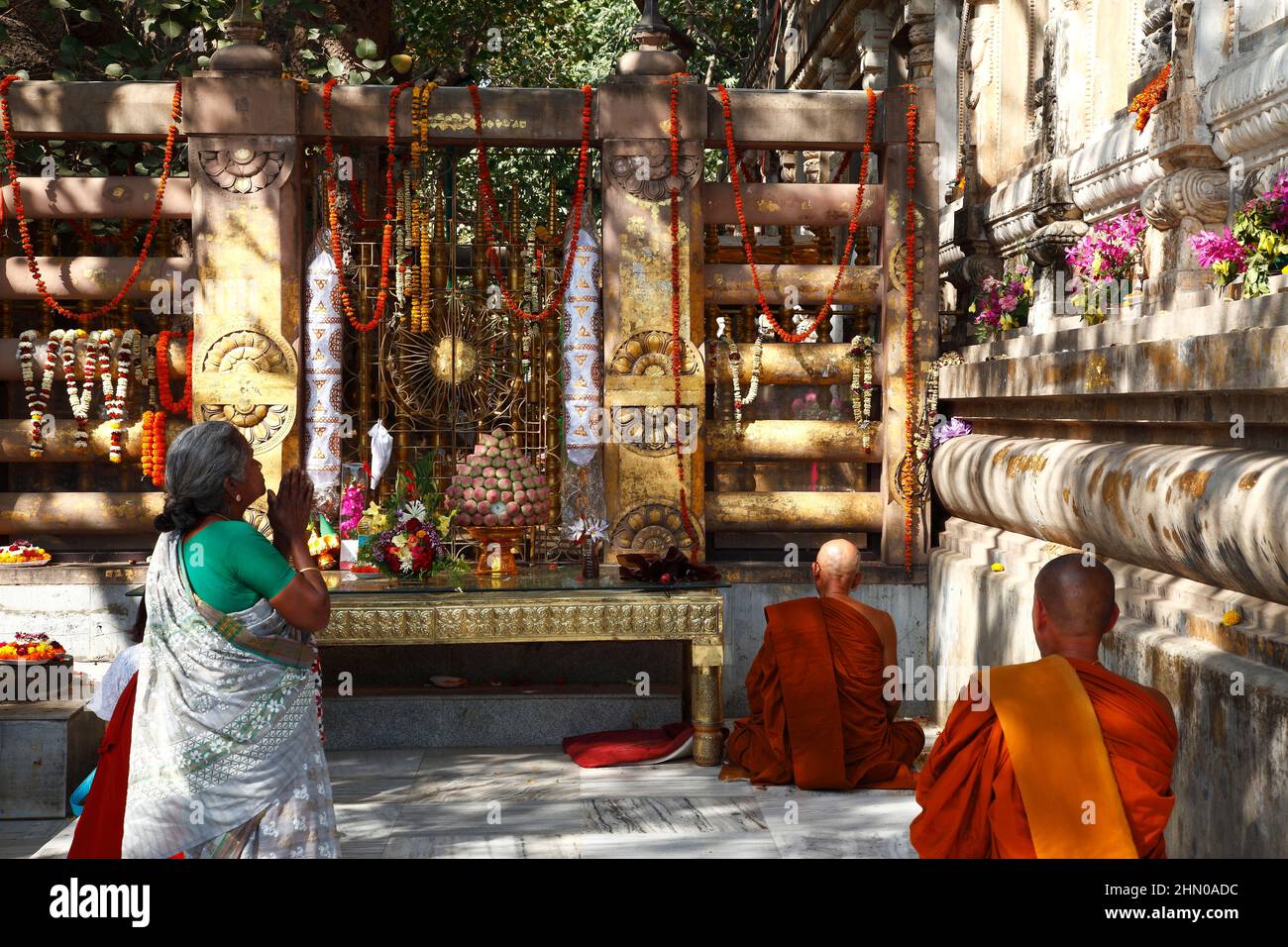 Pilgrims praying to Buddha, gathered around the sacred Bodhi Tree at Mahabodhi Temple, in Bodhgaya, Bihar state, India Stock Photo