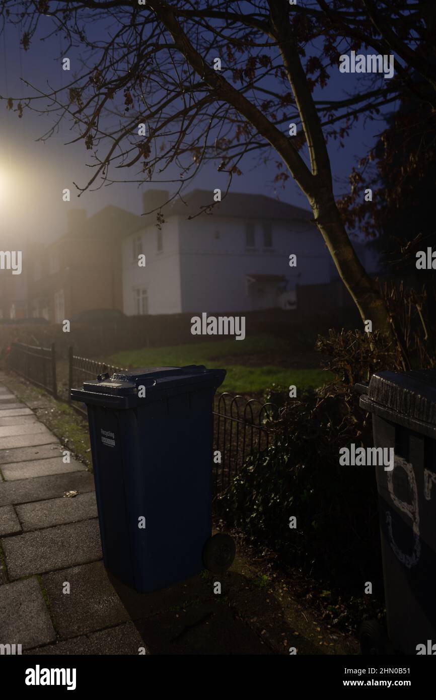 Wheelie bin under street lights on a wet foggy morning in North London, UK Stock Photo