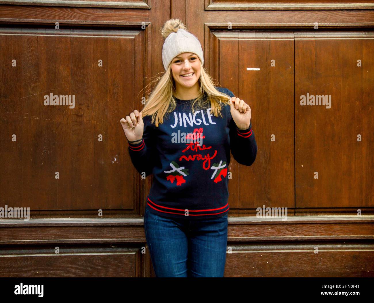 A blond girl in her twenties wearing a christmass sweater and wearing a hat. Stock Photo