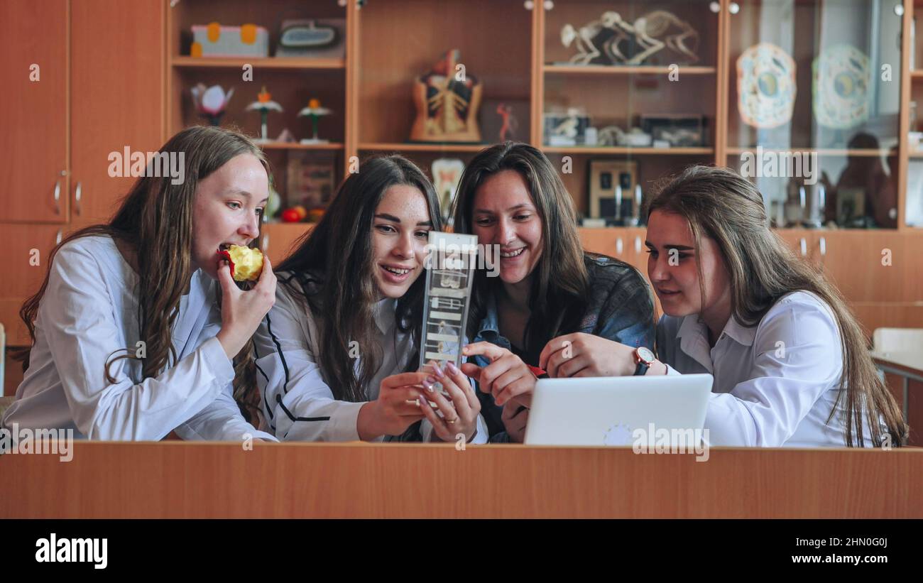Schoolgirls friends working together in class with a laptop and eating ...